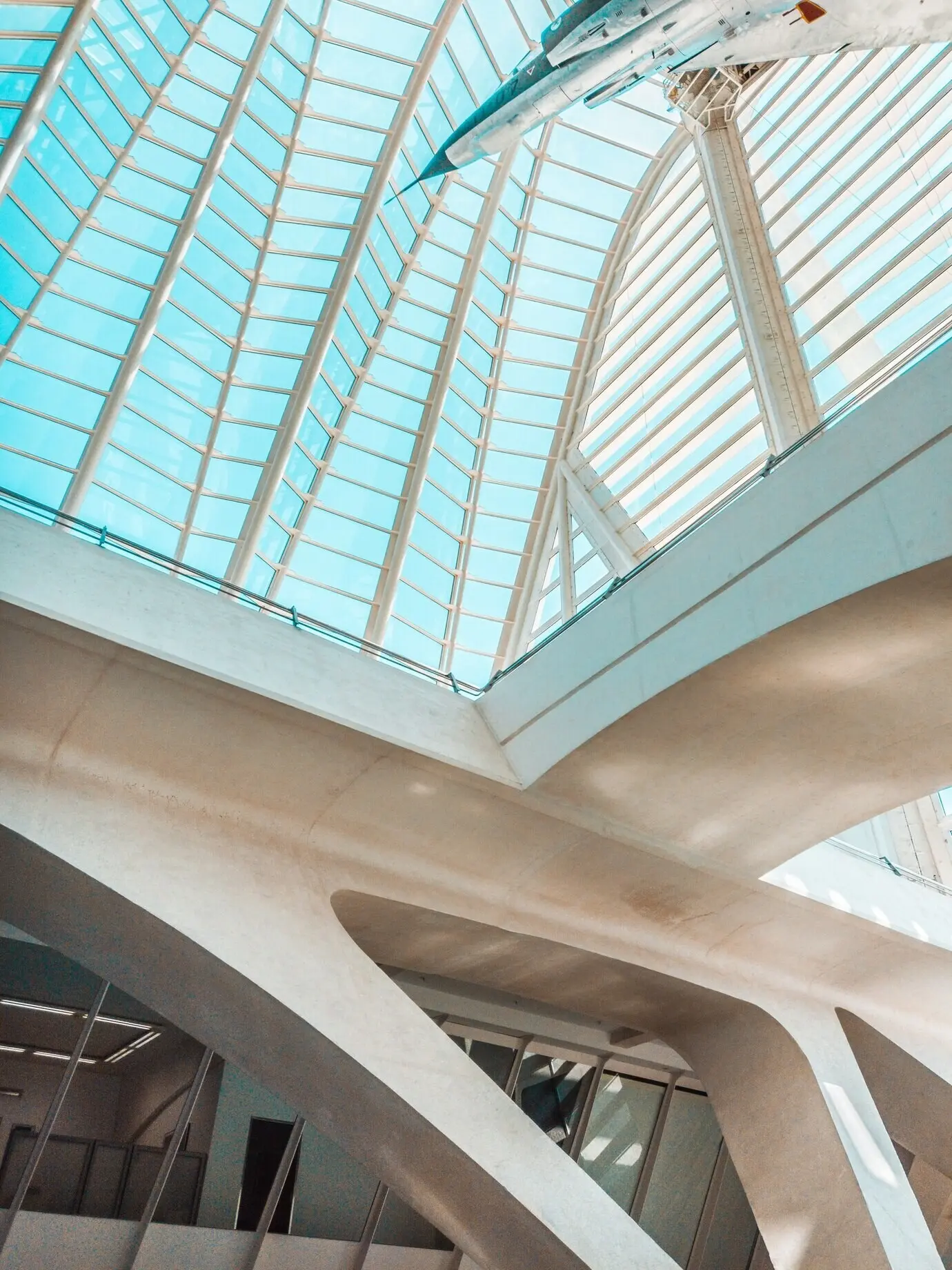 An airplane inside a museum with a glass ceiling.
