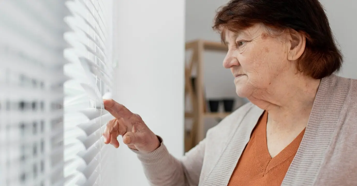 Close-up of an old woman looking out the window.